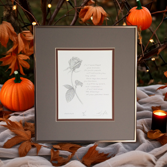 Framed artwork with a rose design and poem, surrounded by pumpkins and autumn leaves.