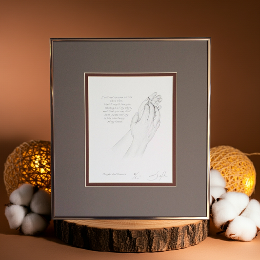 Framed artwork of holding hands on a wooden stand with decorative lights and cotton balls.