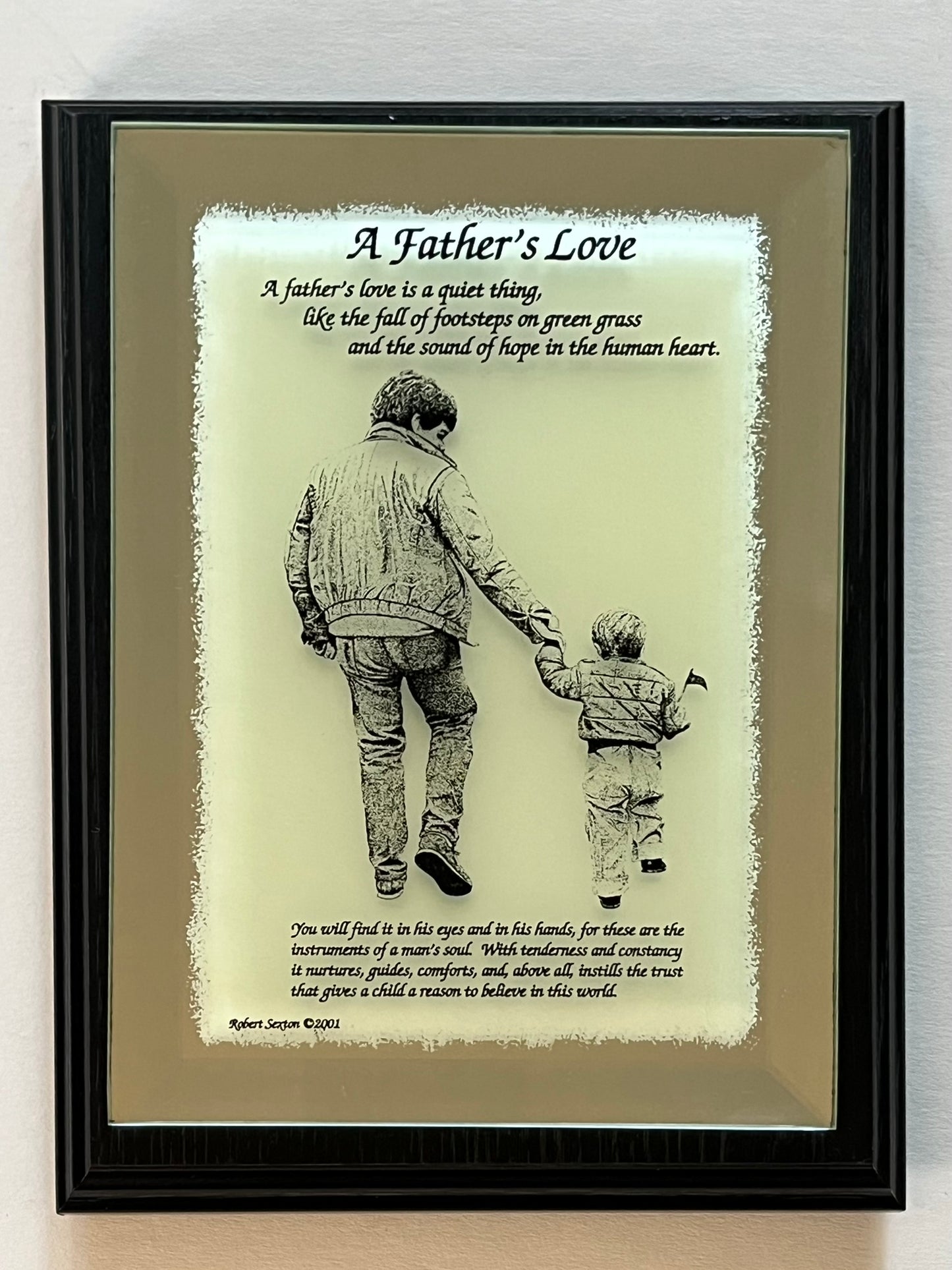 Framed artwork of a father and son holding hands with a quote about father's love.