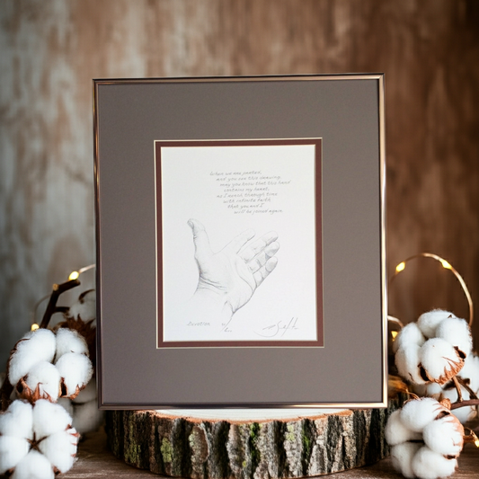 Framed artwork of a handprint on a wooden stump with cotton plants and string lights in the background