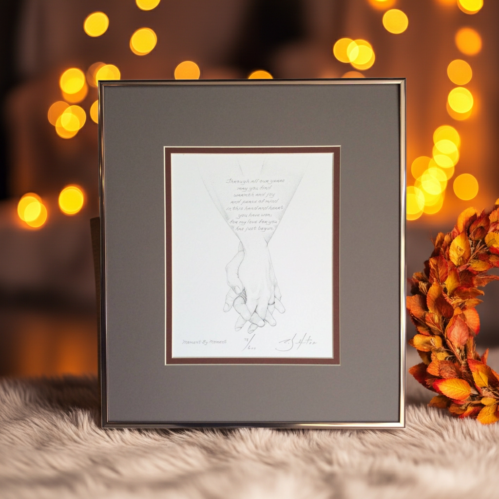 Framed artwork of holding hands on a textured surface with warm bokeh lights in the background