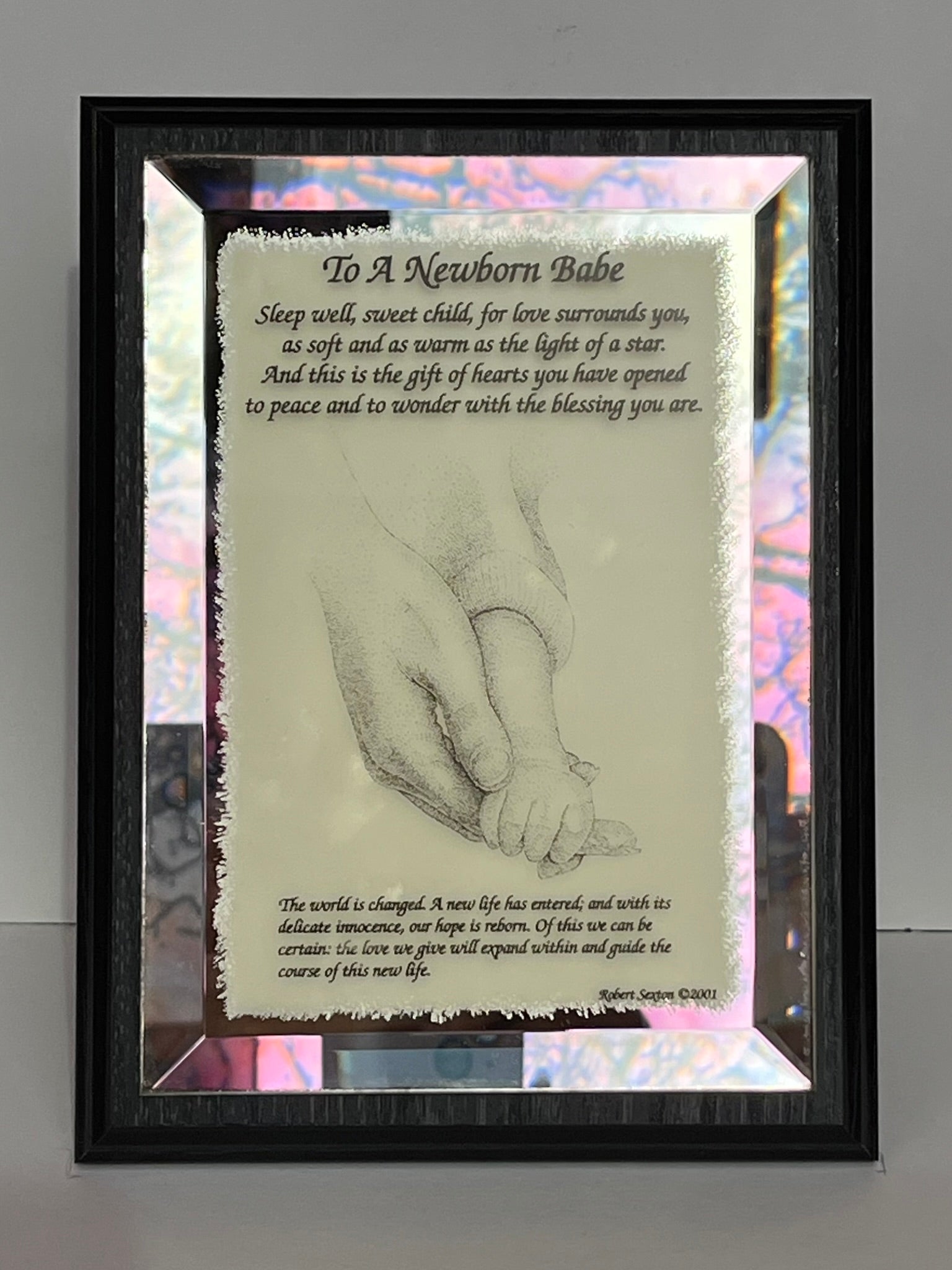 Framed artwork with a hand holding a baby's hand and a poem about a newborn babe.
