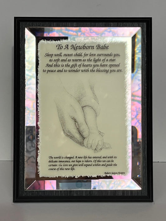 Framed artwork with a hand holding a baby's hand and a poem about a newborn babe.
